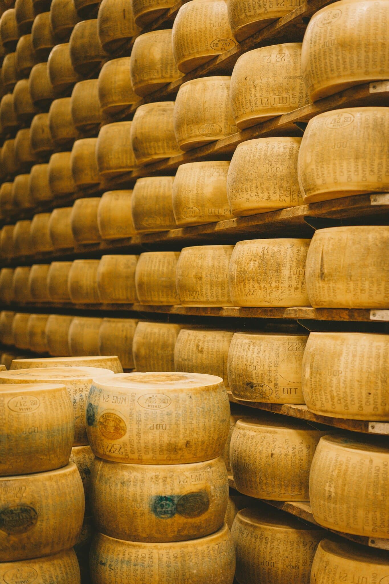 Photo of parmigiano-reggiano stacked in a cheese cave